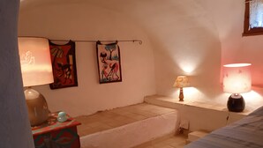 Una habitació acollidora amb un llit, una taula amb una làmpada i dues obres d'art penjades a la paret.