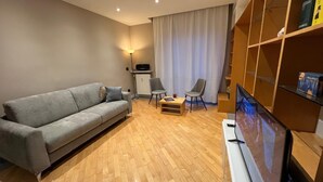 A modern living room with a grey sofa, two armchairs, a coffee table, a flat-screen TV, and a bookshelf. - The Sixteen Suite, elegant apartment in University District, Milan. (Milano)