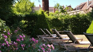Un jardín con sillones de madera y flores florecientes.