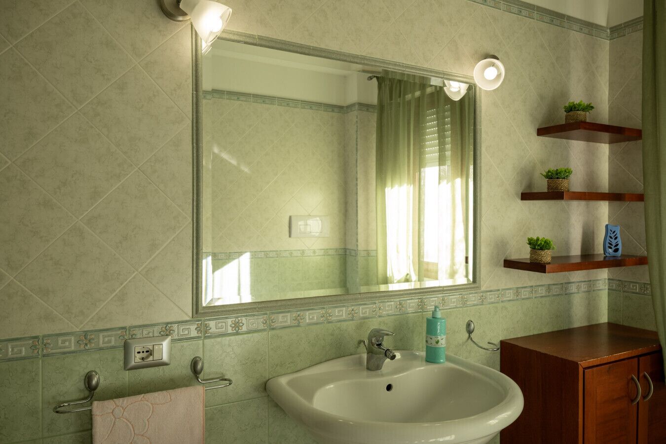 A bathroom with a large mirror, a sink, a towel rack, and wooden shelves with plants.