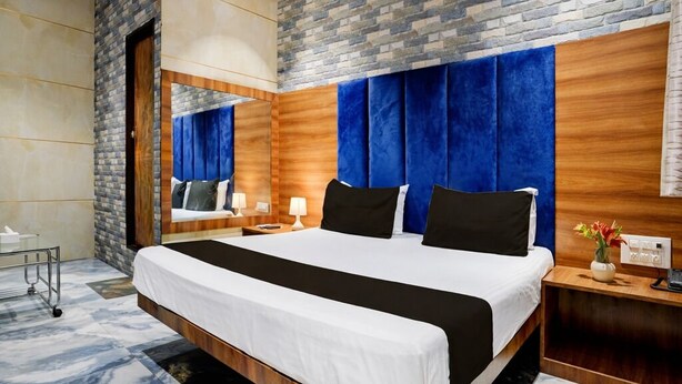 A hotel room with a large bed, a wooden headboard, a brick accent wall, and a marble floor. - Shiv Sai Residency Lodging & Boarding (Vasai)