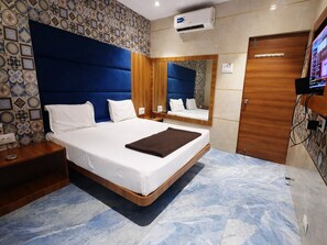 A modern hotel room with a large bed, wooden headboard, a mirror, and a television. - Shiv Sai Residency Lodging & Boarding (Vasai)