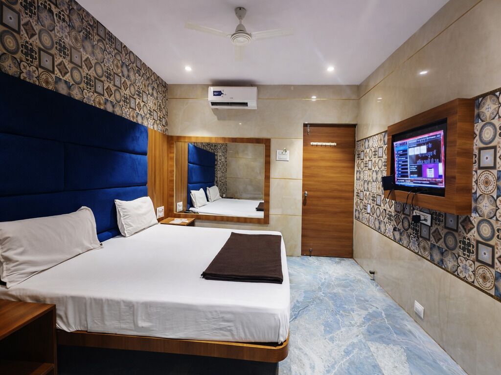 Une chambre d’hôtel avec un grand lit, un ventilateur de plafond, une télévision et un mur décoré d’un motif.