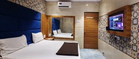 Une chambre d’hôtel avec un grand lit, un ventilateur de plafond, une télévision et un mur décoré d’un motif.