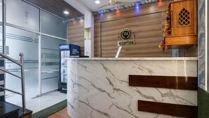 A reception area with a marble counter, a wooden reception desk, and a Pepsi refrigerator. - Shiv Sai Residency Lodging & Boarding (Vasai)
