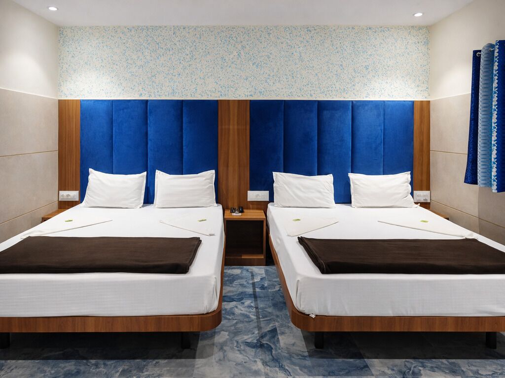 A hotel room with two beds, a wooden headboard, and a patterned ceiling.