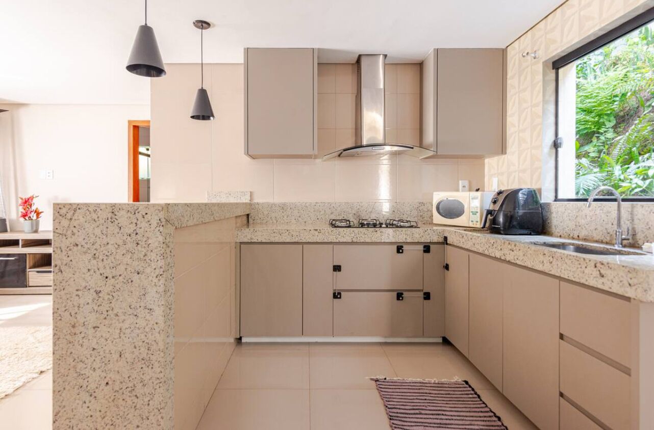 A modern kitchen with granite countertops, stainless steel appliances, and a window with a view of greenery.