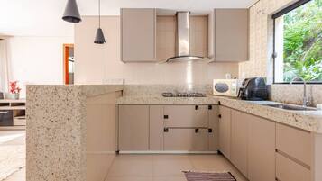 A modern kitchen with granite countertops, stainless steel appliances, and a window with a view of greenery.