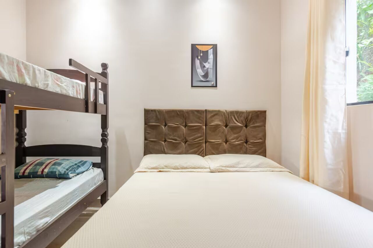 Una habitación con literas, una cama individual y un cuadro en la pared.