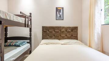 Una habitación con literas, una cama individual y un cuadro en la pared.