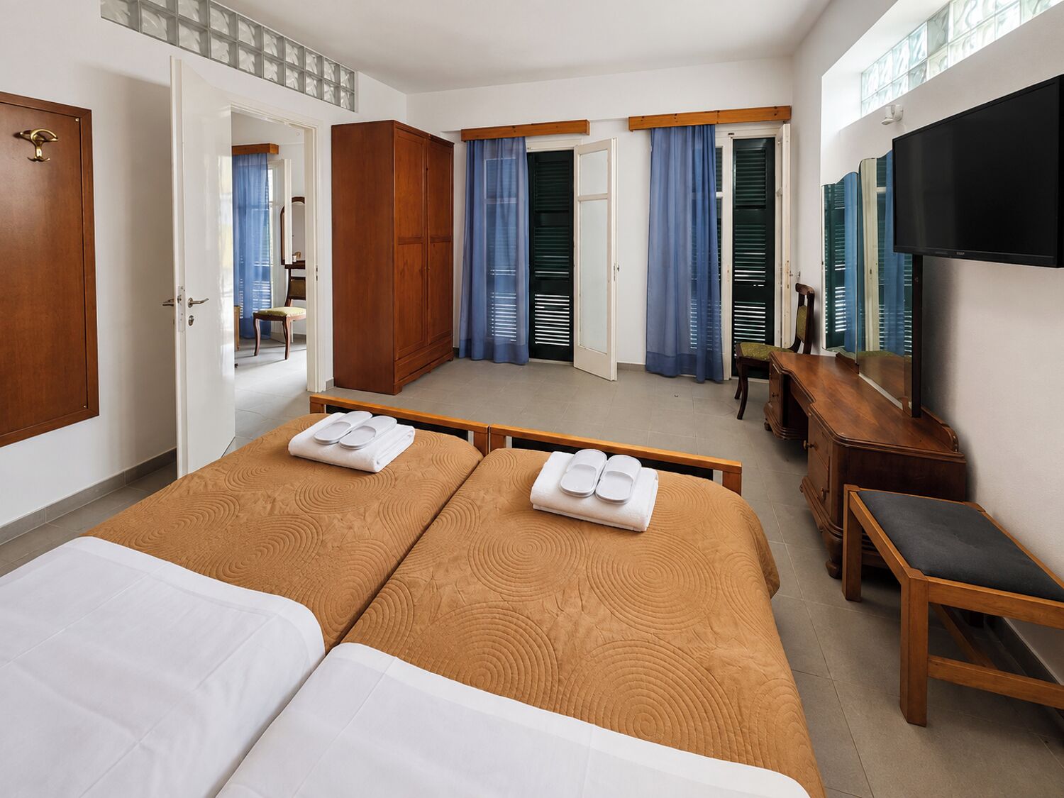 Une chambre d’hôtel avec deux lits, un bureau, une télévision et une armoire.