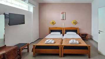 A hotel room with two wooden beds, a TV mounted on the wall, and a desk with a chair.