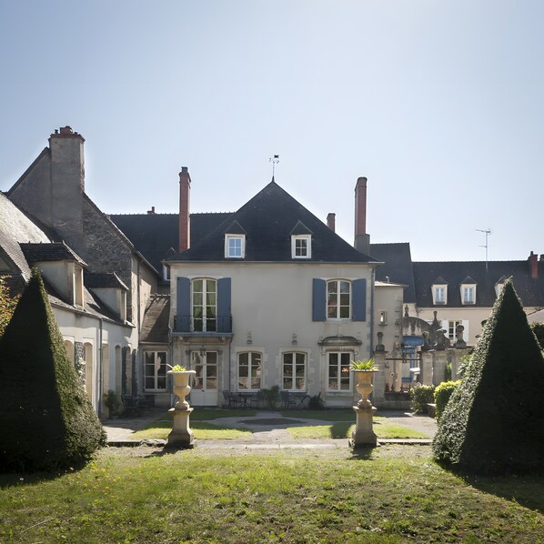 Une maison à deux étages, dotée d’une façade symétrique, d’une entrée centrale et d’un petit balcon.