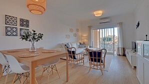 Un salon moderne avec un coin repas, des meubles blancs et des œuvres d’art décoratives au mur.