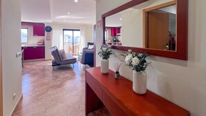 A modern hotel room with a wooden console table, a large mirror, and two vases with flowers. - Ocean View Quarteira (Loulé)