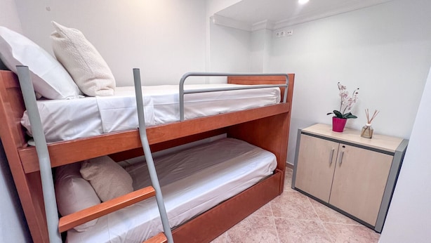 A bunk bed with a lower bunk, a small cabinet, and a potted orchid. - Ocean View Quarteira (Loulé)