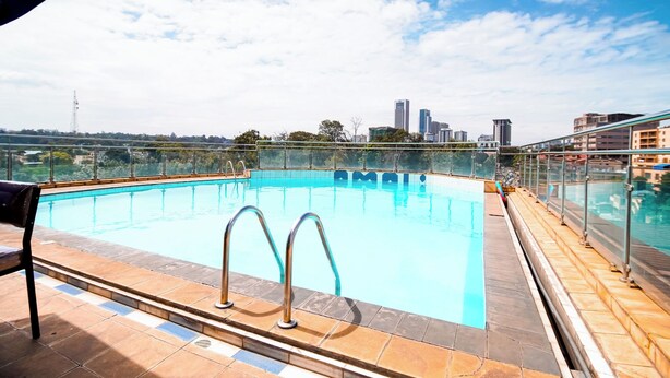 Ein Pool auf dem Dach mit klarem, blauem Wasser, Metallgeländern und einer Stadtansicht im Hintergrund.