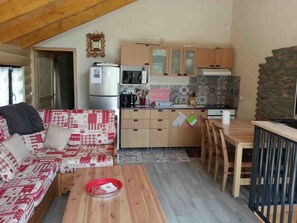 Une cuisine chaleureuse avec des meubles de rangement en bois, un réfrigérateur et un coin repas comprenant une table et des chaises.