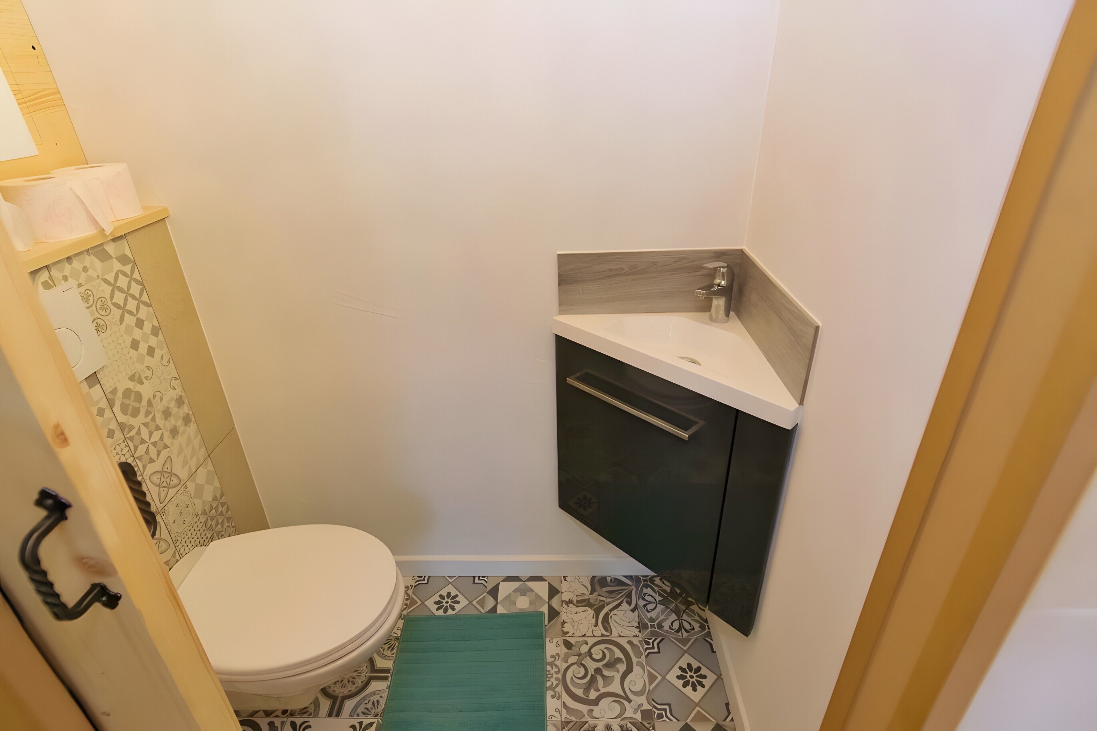 Ein kleines Badezimmer mit Toilette, Waschbecken und Fliesen mit Muster.