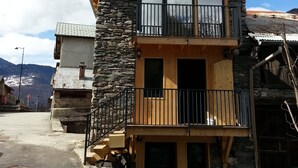 Un immeuble de deux étages avec une façade en pierre, un balcon et une vue sur le paysage environnant.