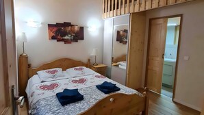 Une chambre à coucher avec un cadre en bois, comprenant un lit, des tables de chevet, un miroir et une clôture en bois.