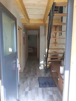 A hallway with a wooden ceiling, a staircase, and a door with a handle. - Charming 3-Star Mountain Chalet – Skiing & Spa Retreat (Courchevel)
