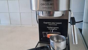 A compact, modern coffee maker with a digital pressure gauge, a small cup holder, and a sleek design.