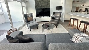 A modern living room with a grey sofa, ottoman, and armchair, a flat-screen TV, and a large patterned wall. - Modern and Stylish apartment in downtown Reykjavik - Great location ! (Reykjavik)