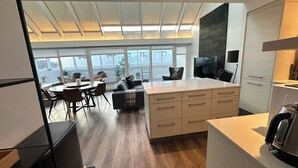 A modern kitchen with a central island, dining area with chairs, and large windows offering a view of the outdoors. - Modern and Stylish apartment in downtown Reykjavik - Great location ! (Reykjavik)