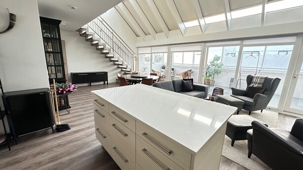 A spacious living area with a large white island, a staircase, and a view of the city through large windows. - Modern and Stylish apartment in downtown Reykjavik - Great location ! (Reykjavik)