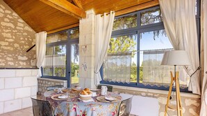 Un comedor con una mesa dispuesta para dos, una lámpara y un ventanal con cortinas.
