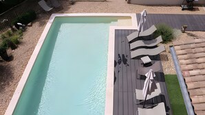A rectangular swimming pool with a wooden deck and lounge chairs. - “Grand Gîte” with Mountain View, Shared Pool, and Wi-Fi (Saint-Jean du Gard)