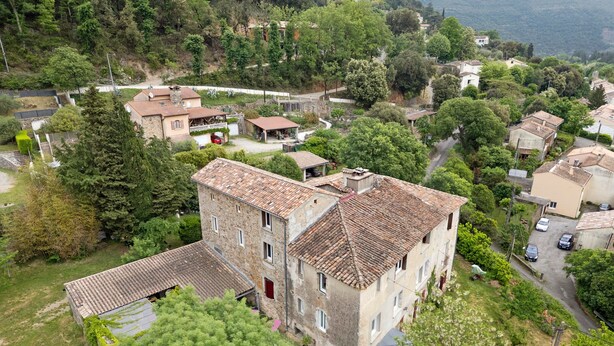 A multi-story building with a tiled roof, surrounded by greenery and other residential buildings. - “Grand Gîte” with Mountain View, Shared Pool, and Wi-Fi (Saint-Jean du Gard)