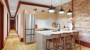 Una cocina moderna con una isla central, electrodomésticos de acero inoxidable, armarios de madera e iluminación colgante.