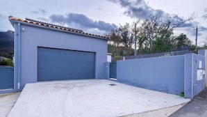 A building with a large garage door, a concrete driveway, and a blue wall.