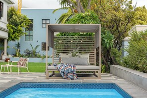 A poolside area with a covered seating area, a tiled pool, and surrounding greenery. - Disandt House by Neighbourgood (Cape Town)