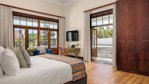 A bedroom with a large bed, a desk, a TV, and a view of the outdoors. - Disandt House by Neighbourgood (Cape Town)