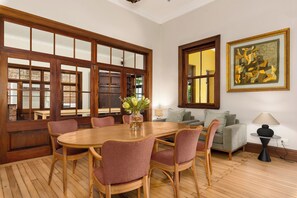 A dining area with a wooden table and chairs, a sofa, and a painting on the wall. - Disandt House by Neighbourgood (Cape Town)