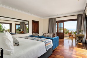 Habitación de hotel con una cama grande, un escritorio, una silla y un balcón con vistas.