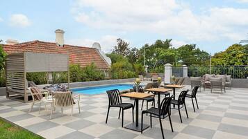 Un patio exterior con piscina, suelo a cuadros y mobiliario de exterior.