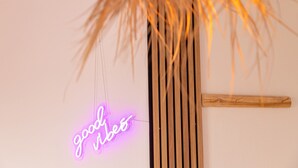 Une enseigne au néon avec l’inscription « bonnes ondes » et une structure en lattes de bois.