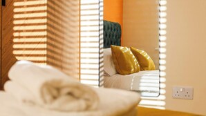 A neatly made bed with a white duvet and a rolled towel, a green upholstered headboard, and two yellow pillows. - Spacious 5-bed Contractor House - Parking Wi-fi (Coventry)
