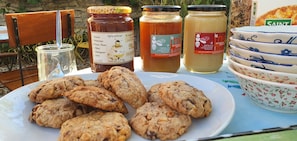 A plate of cookies, jars of honey, and a bowl of fruit on a table. - Guest Room 'Églantine' in Courçon – Sleeps 4, Breakfast Included (Courçon)