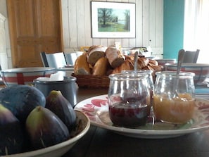 A dining table with bread, fruits, and jars of preserves. - Guest Room 'Églantine' in Courçon – Sleeps 4, Breakfast Included (Courçon)