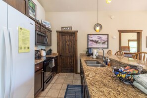 Cocina equipada con refrigerador, microondas, horno y encimera de granito.