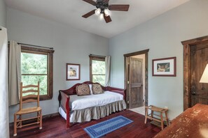 Ein Schlafzimmer mit einem Bett, zwei Stühlen, einer Holztür und einem Deckenventilator.