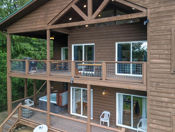 Una cabaña de madera de varios niveles con balcones, asientos exteriores y un patio.
