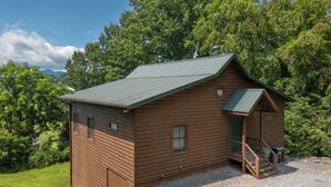 Eine Holzhütte mit geneigtem Dach, einer Veranda mit Geländer und einem Schotterweg.