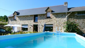 Un bâtiment en pierre doté d’une piscine, d’un espace extérieur aménagé et d’une échelle pour y accéder.