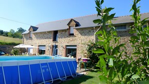 Un edificio de piedra con piscina, terraza cubierta y jardín.